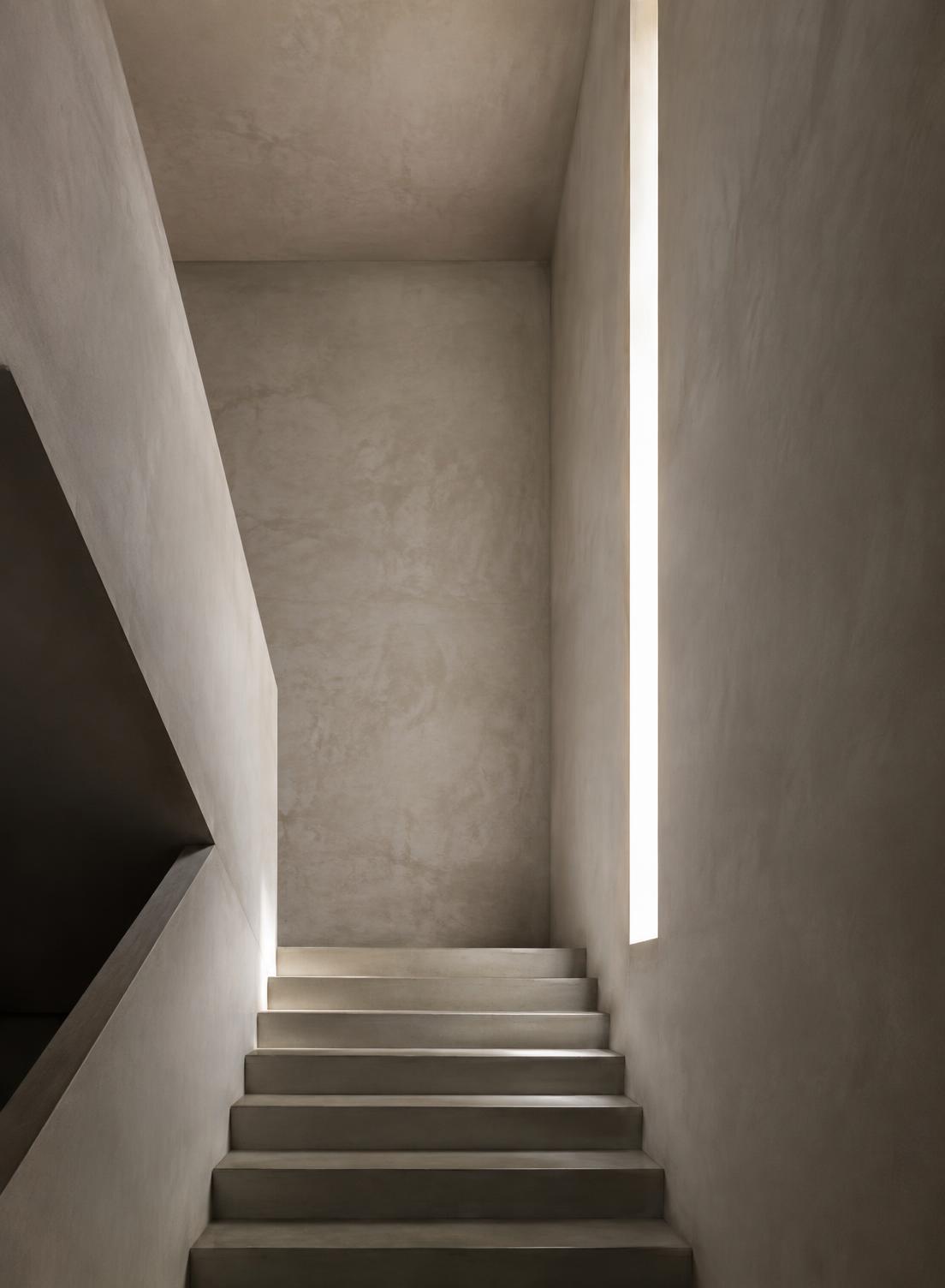 Minimal interior stairwell with plaster walls and a vertical light slot